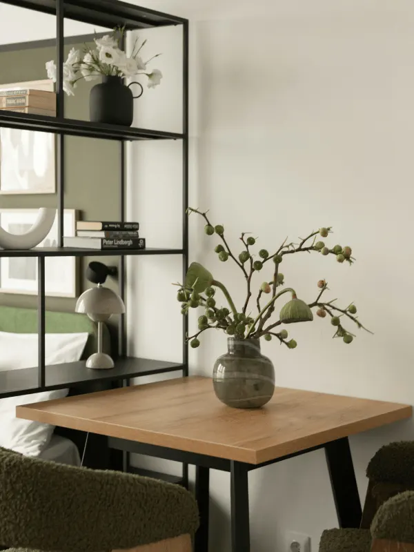Une table en bois carré avec deux chaises et une fausse plante en décoration.
