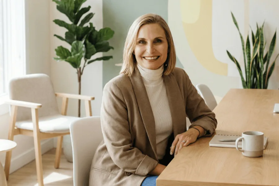 Une femme est assise à une table dans son salon.