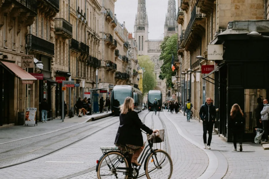 Photo d'une femme faisant du vélo le long de la rue Vital Carles à Bordeaux avec au loin la Cathédrale Saint-André de Bordeaux
